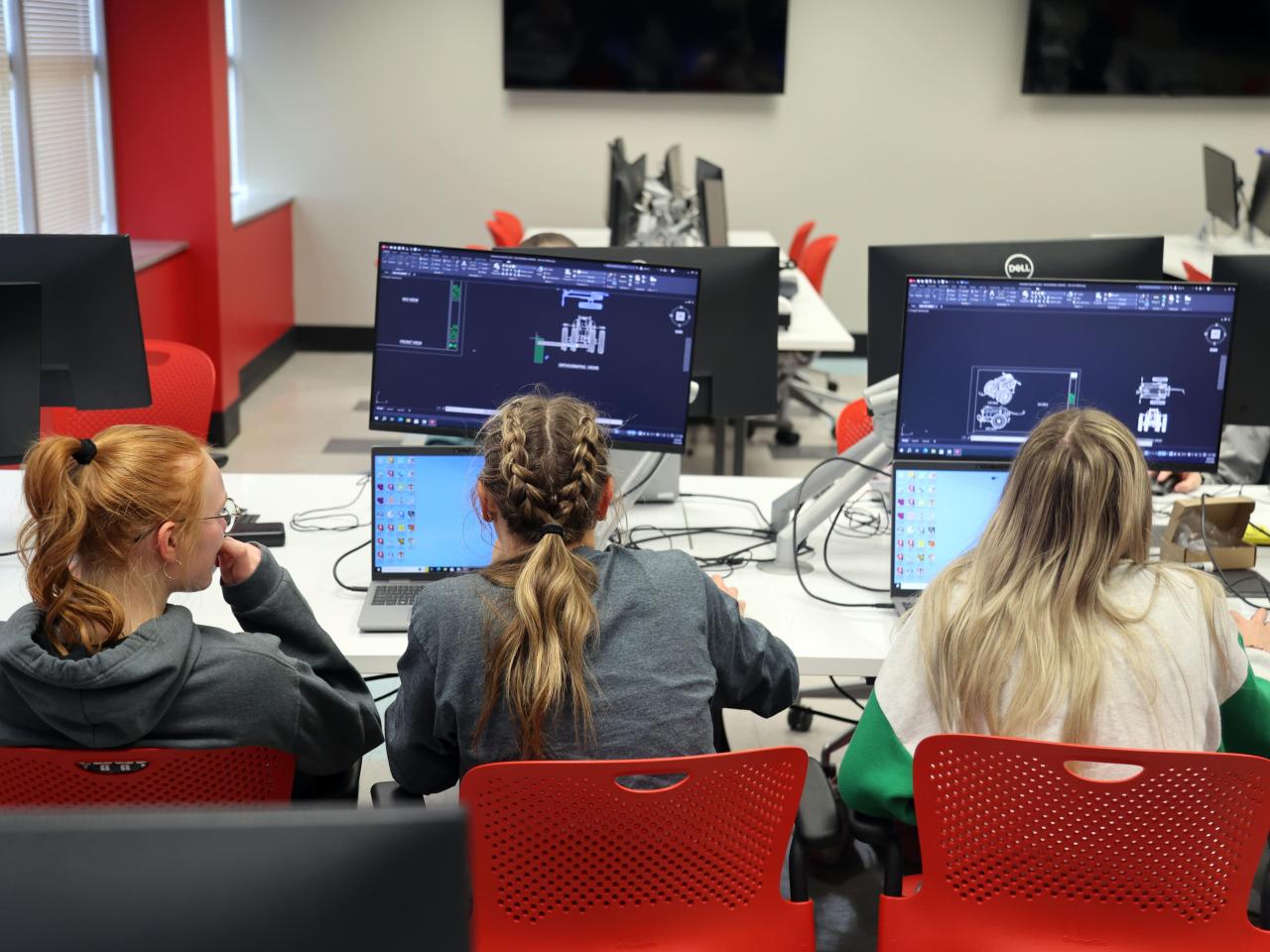 Three students practice autocad on computers