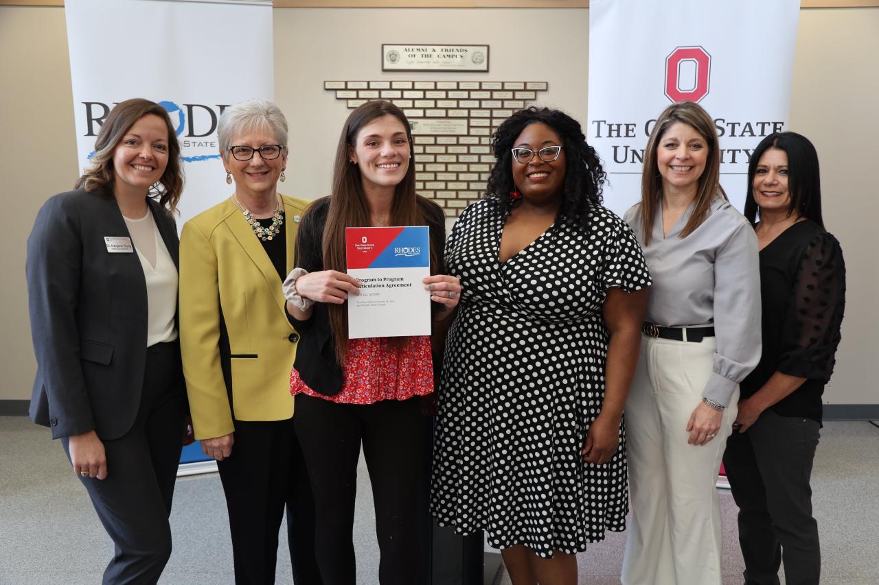 Six speakers in front of Ohio State and Rhodes banners