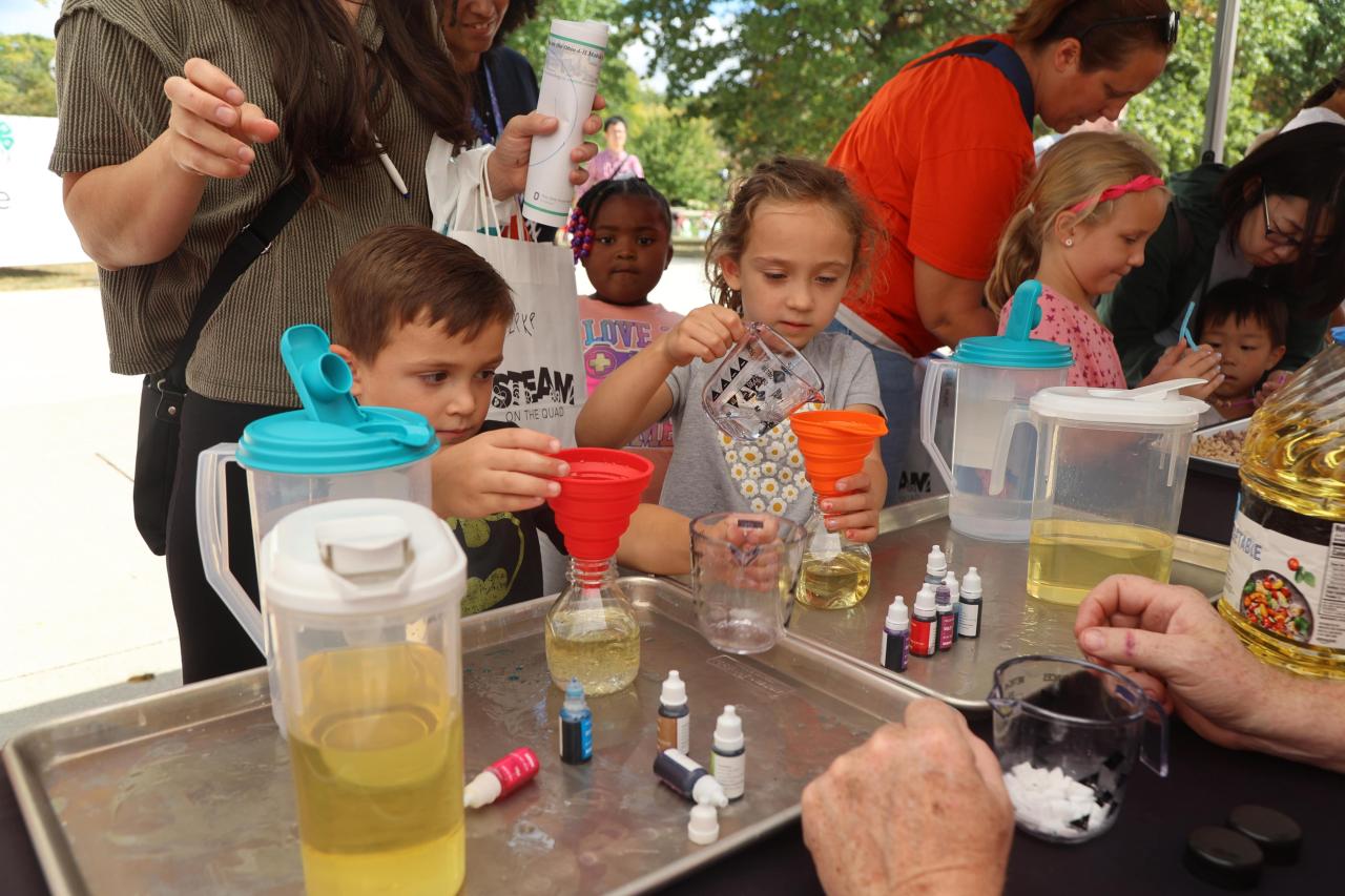 Two STEAM on the Quad participants measure liquids into a beaker 