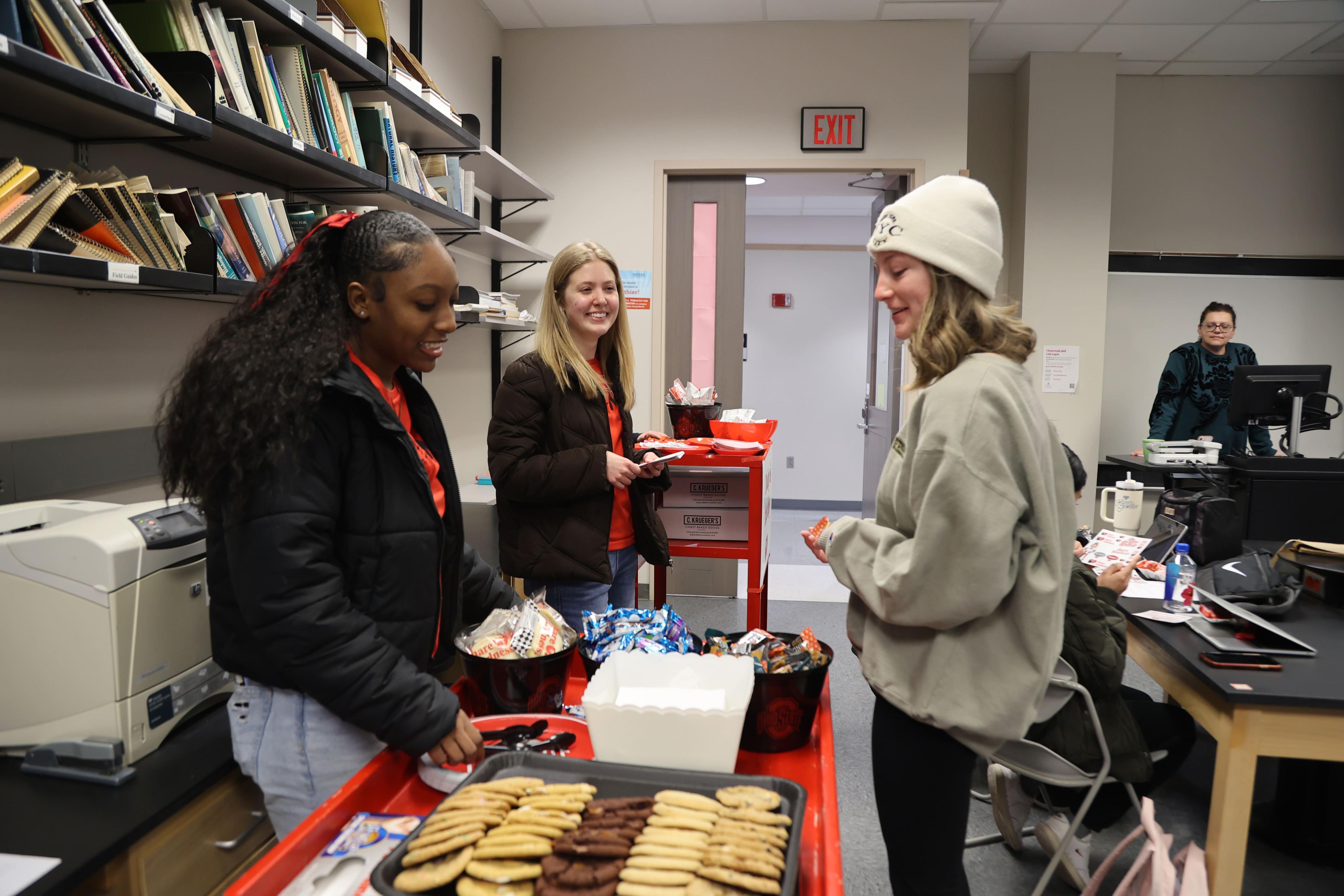 Students pass out cookies and snacks in a classroom