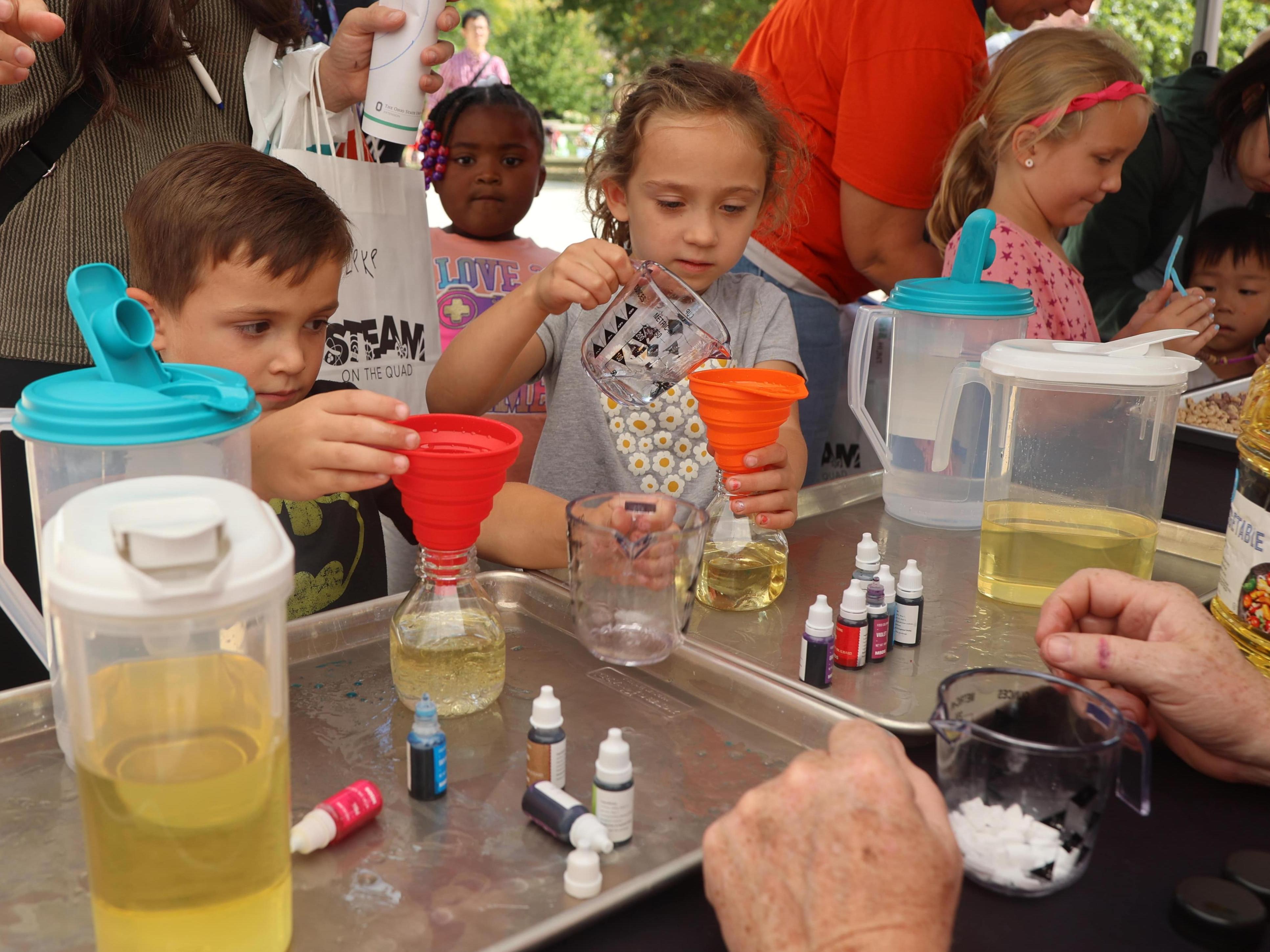 Two STEAM on the Quad participants measure liquids into a beaker 