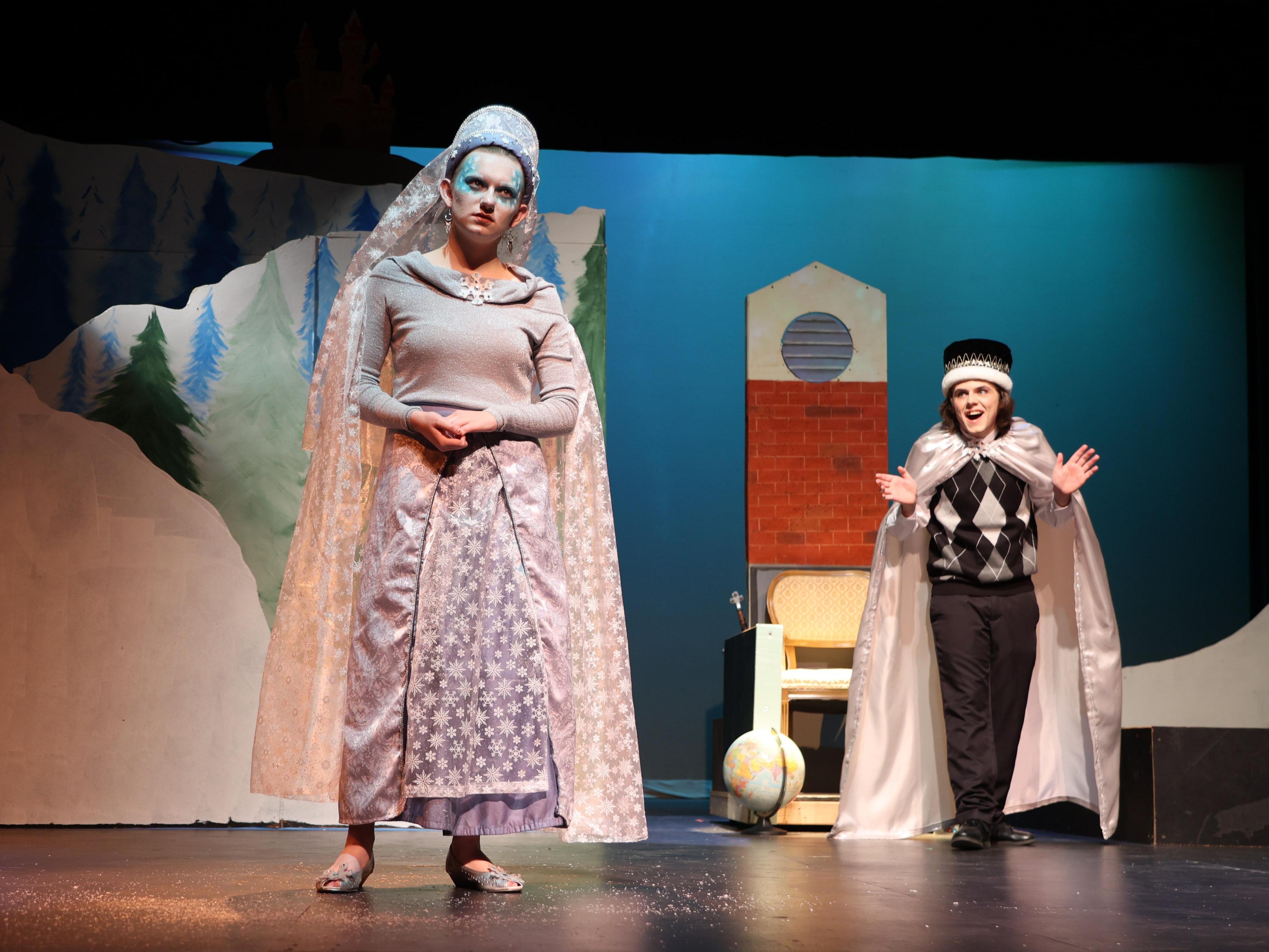 The Snow Queen stands in front of a boy wearing a crown and acting snotty.