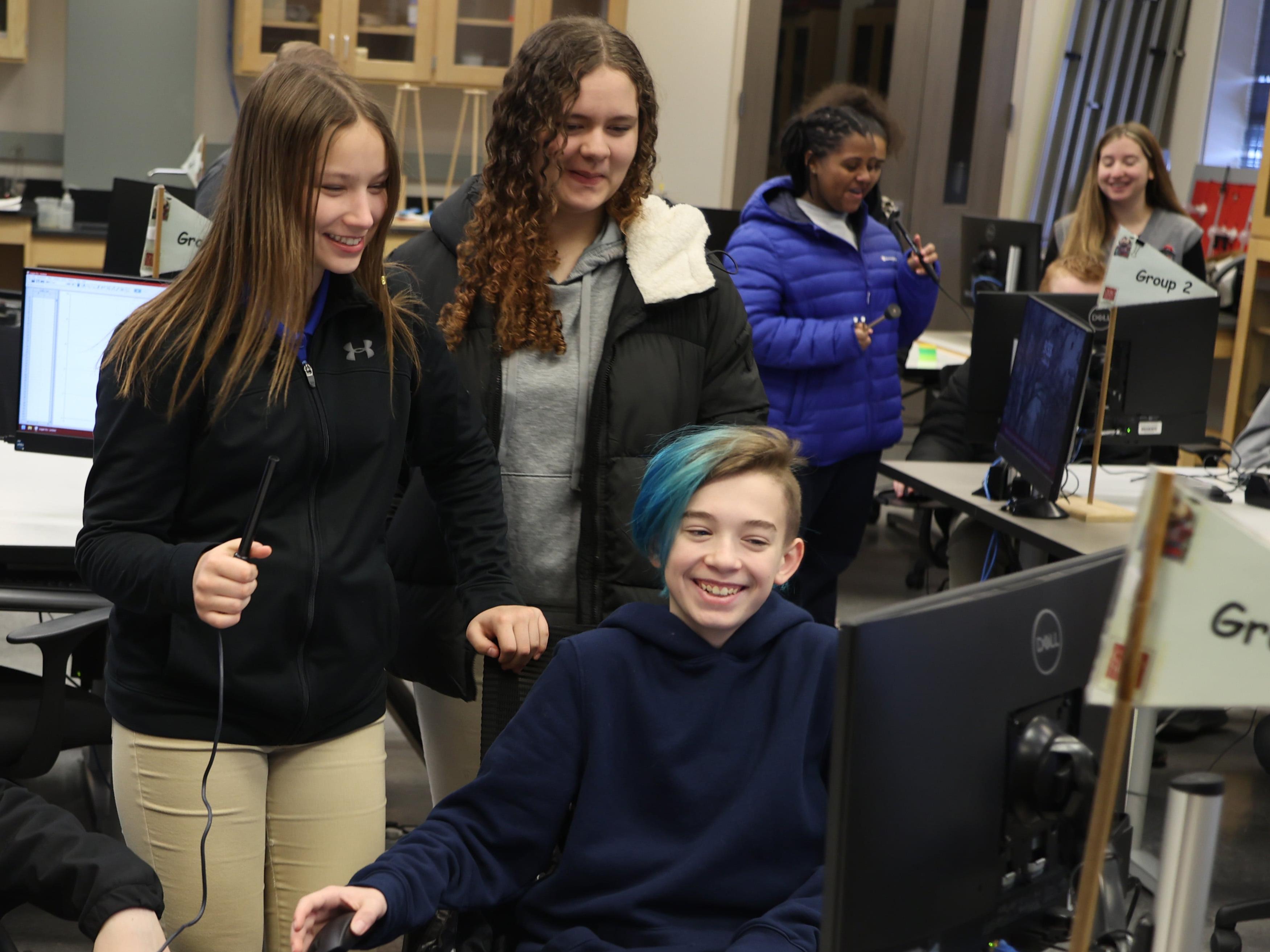 Students laughing around a computer monitor in a science lab