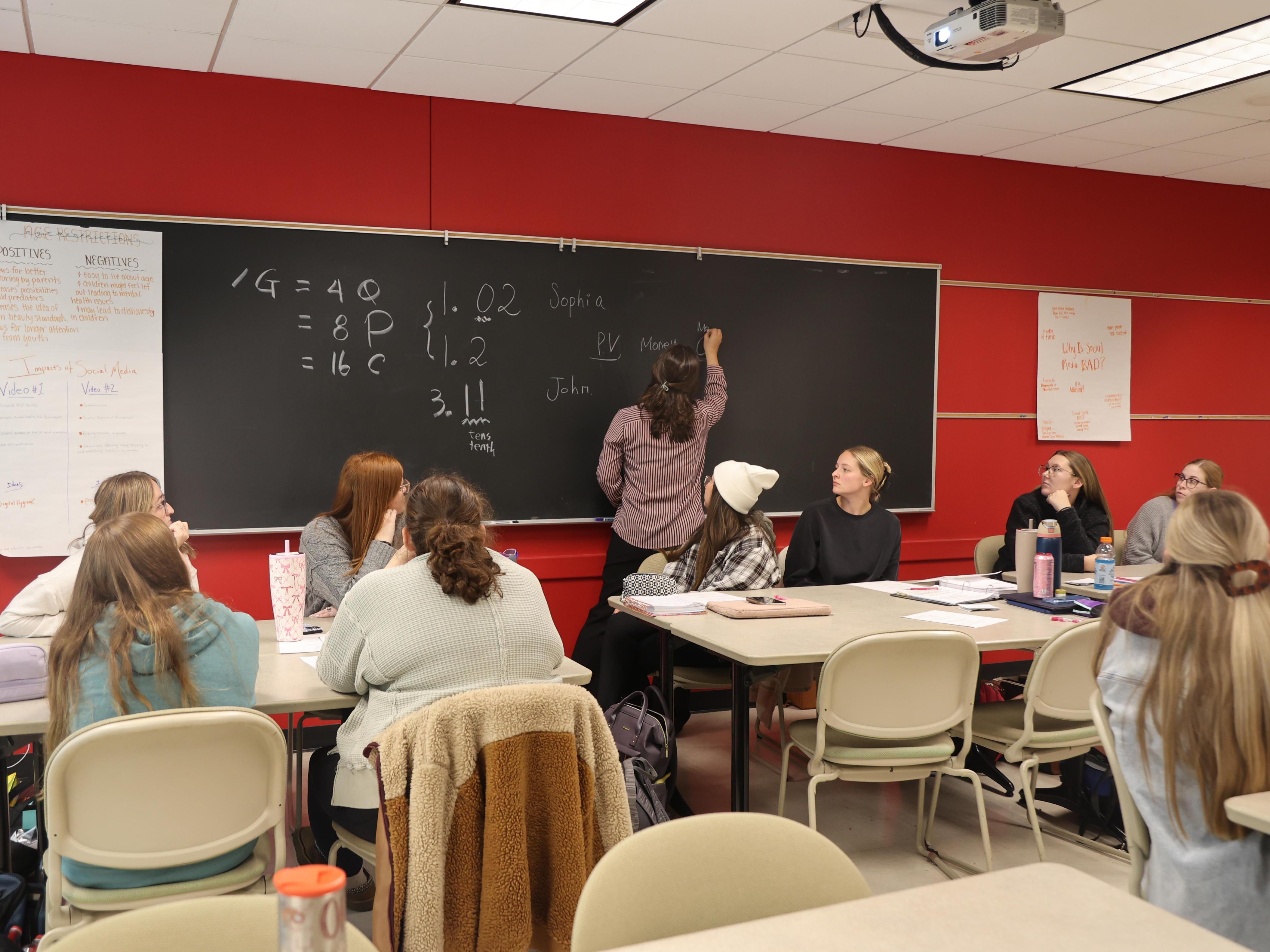 A professor explains a math concept to a group of college students