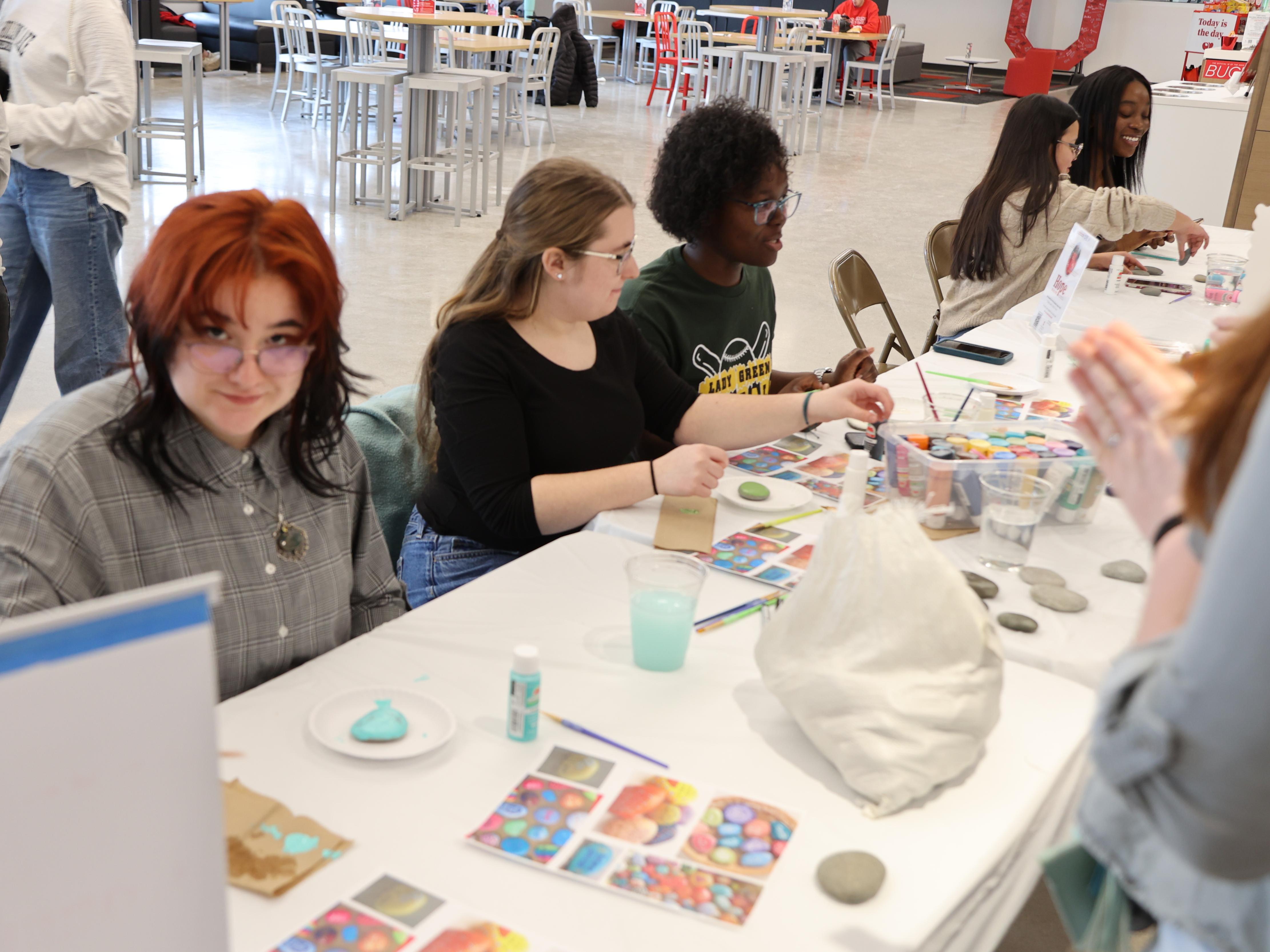 A tableful of students paint kindess rocks