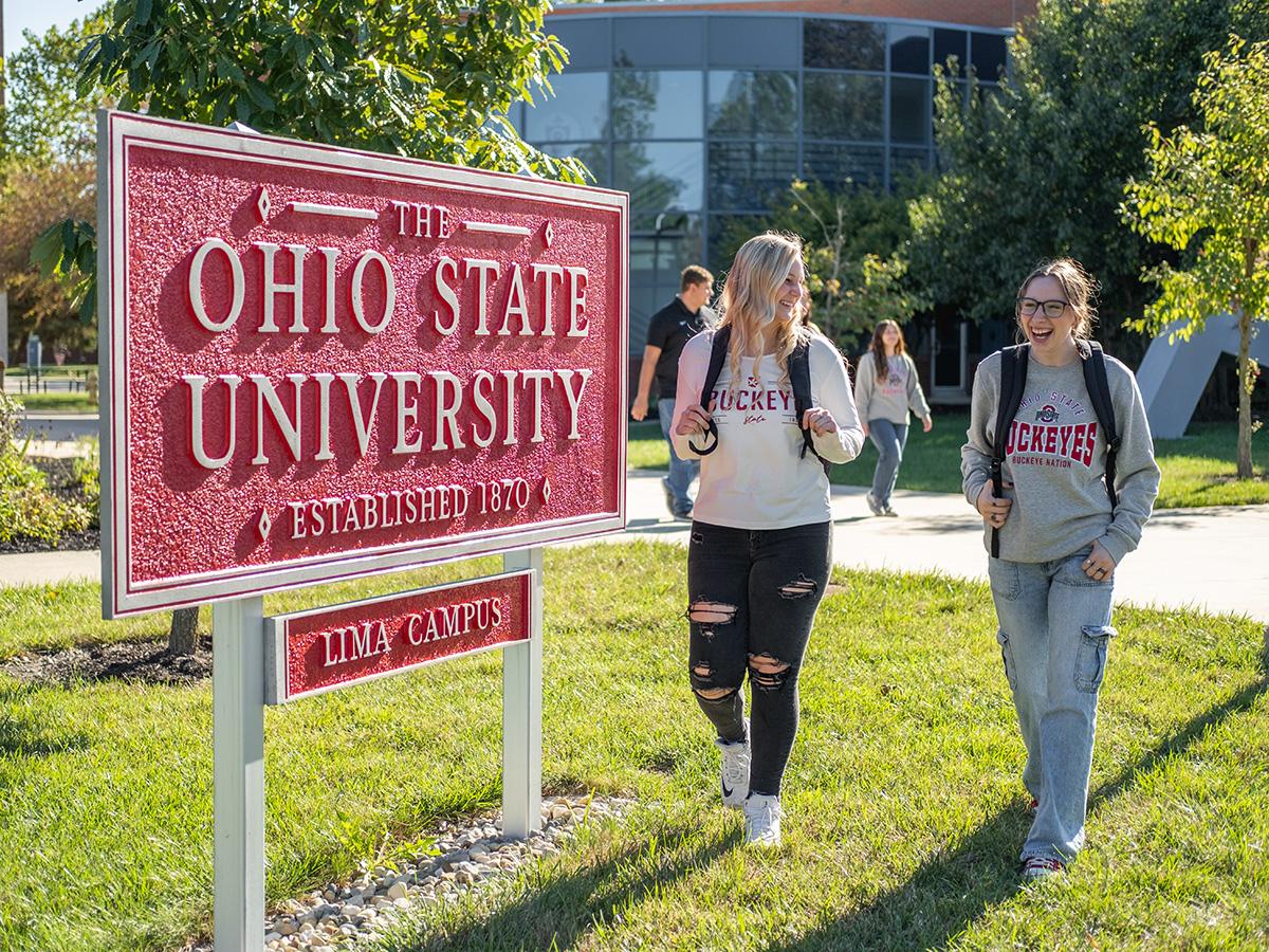 Two students walk by a red sign that says The Ohio State University, Lima Campus