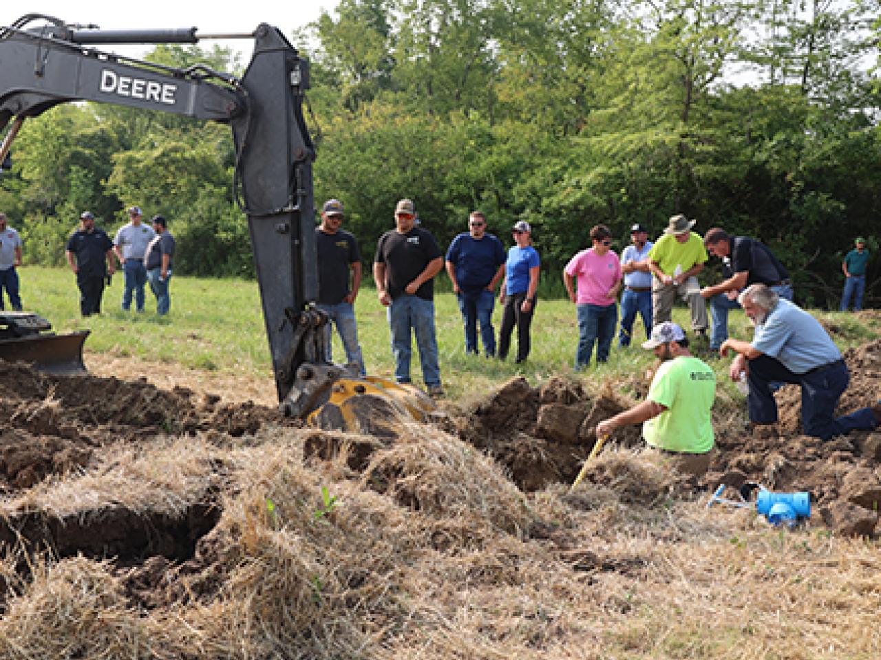 Spectators watch tile being put in a farm field