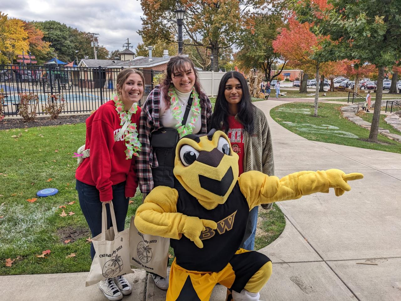 Three students with a bee mascot