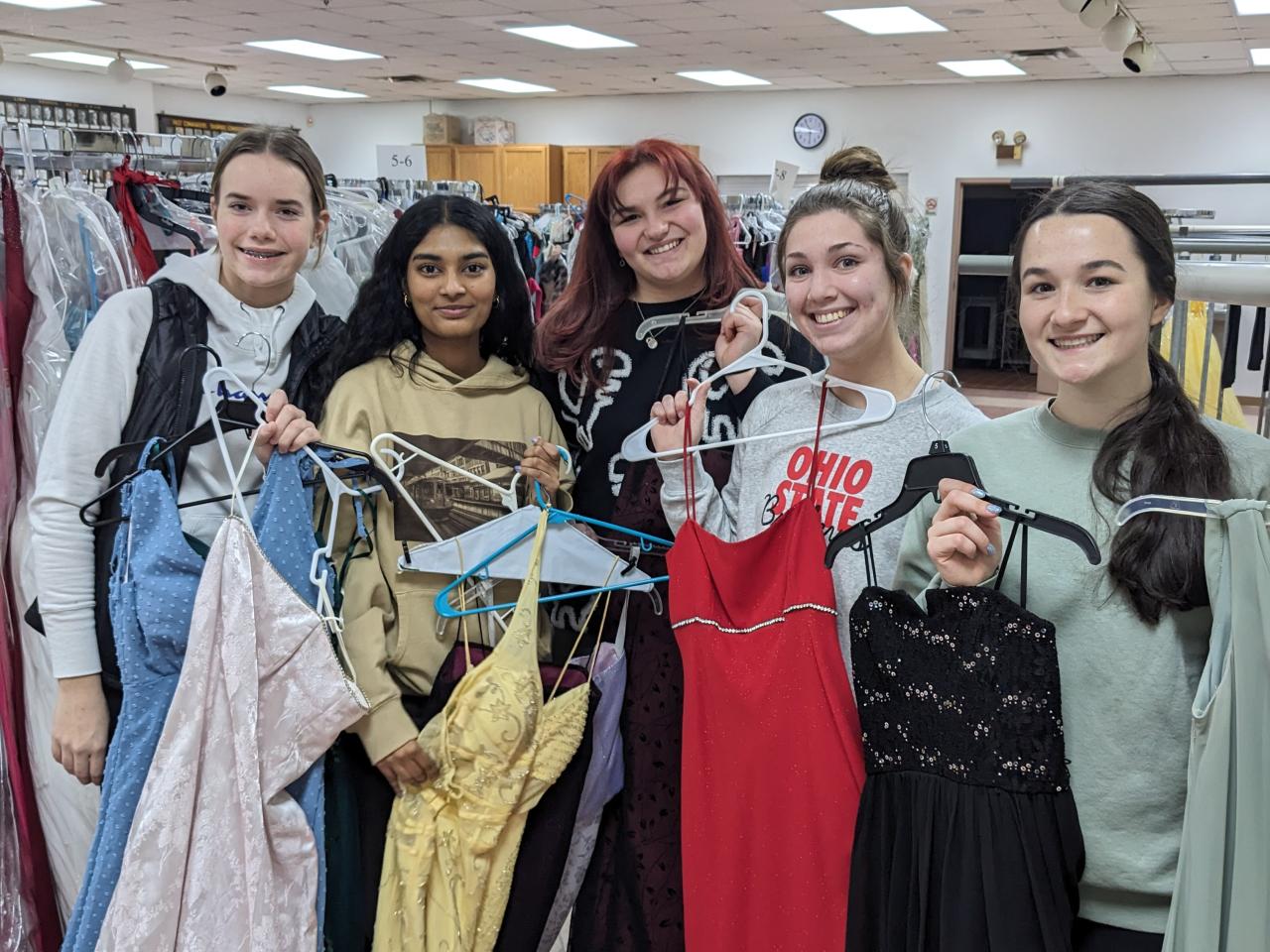 five girls holding prom dresses