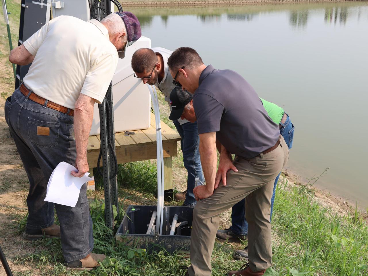 Drainage day participants examine components by the pond