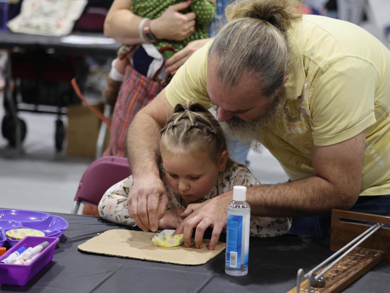 Adult helping a child at a STEAM on the Quad table