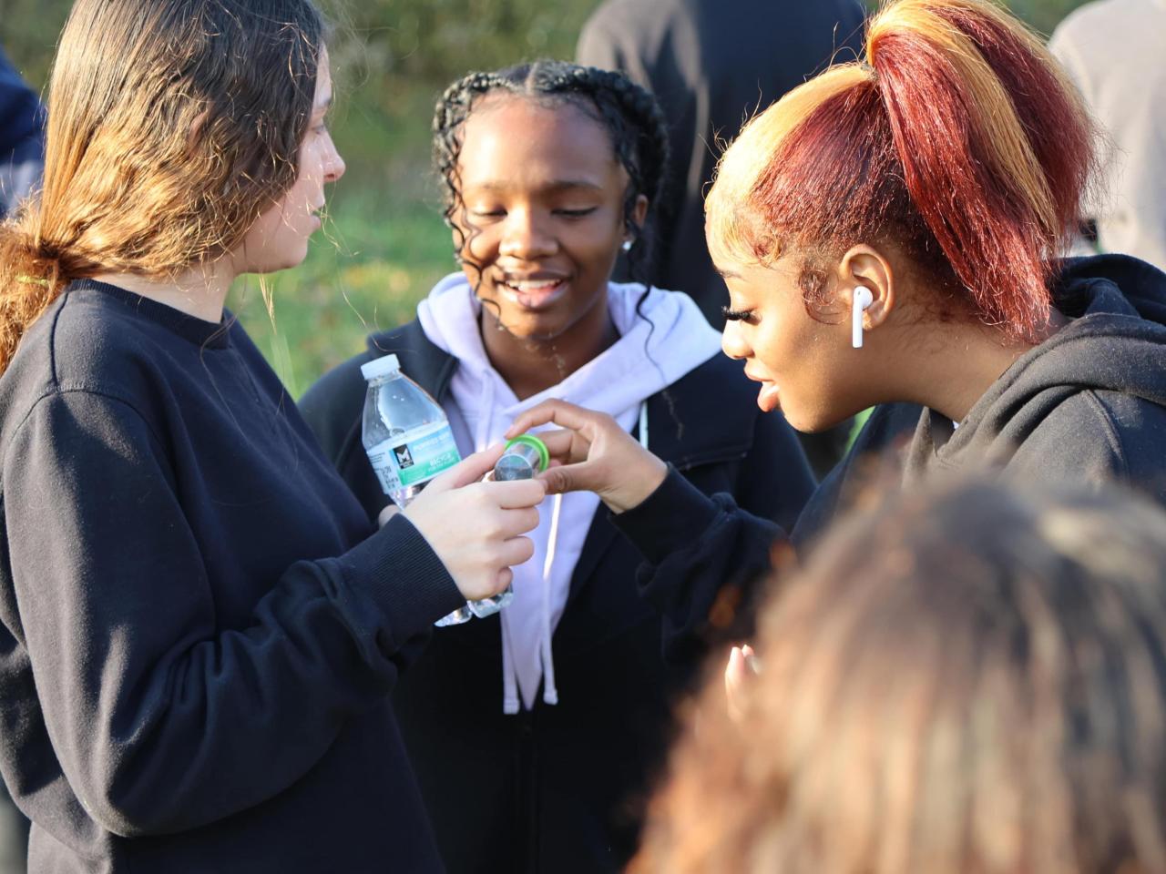 Three girls examine a container of insects at Ohio State Lima's regenerative farm