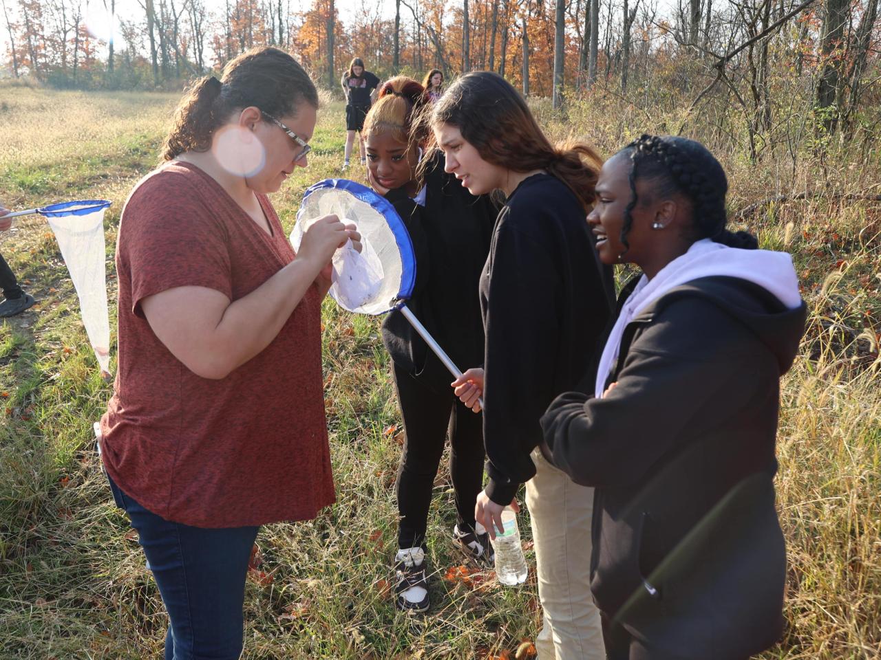 Students hold the insect net while a professor looks for insects. 