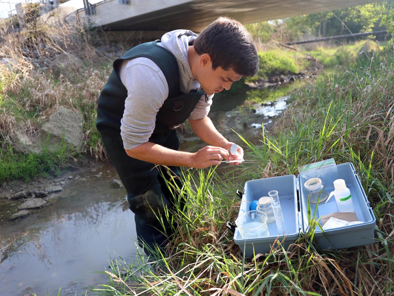 Undergraduate researcher Carter Welch installs a filter in a glass container to test water from the Lost Creek.