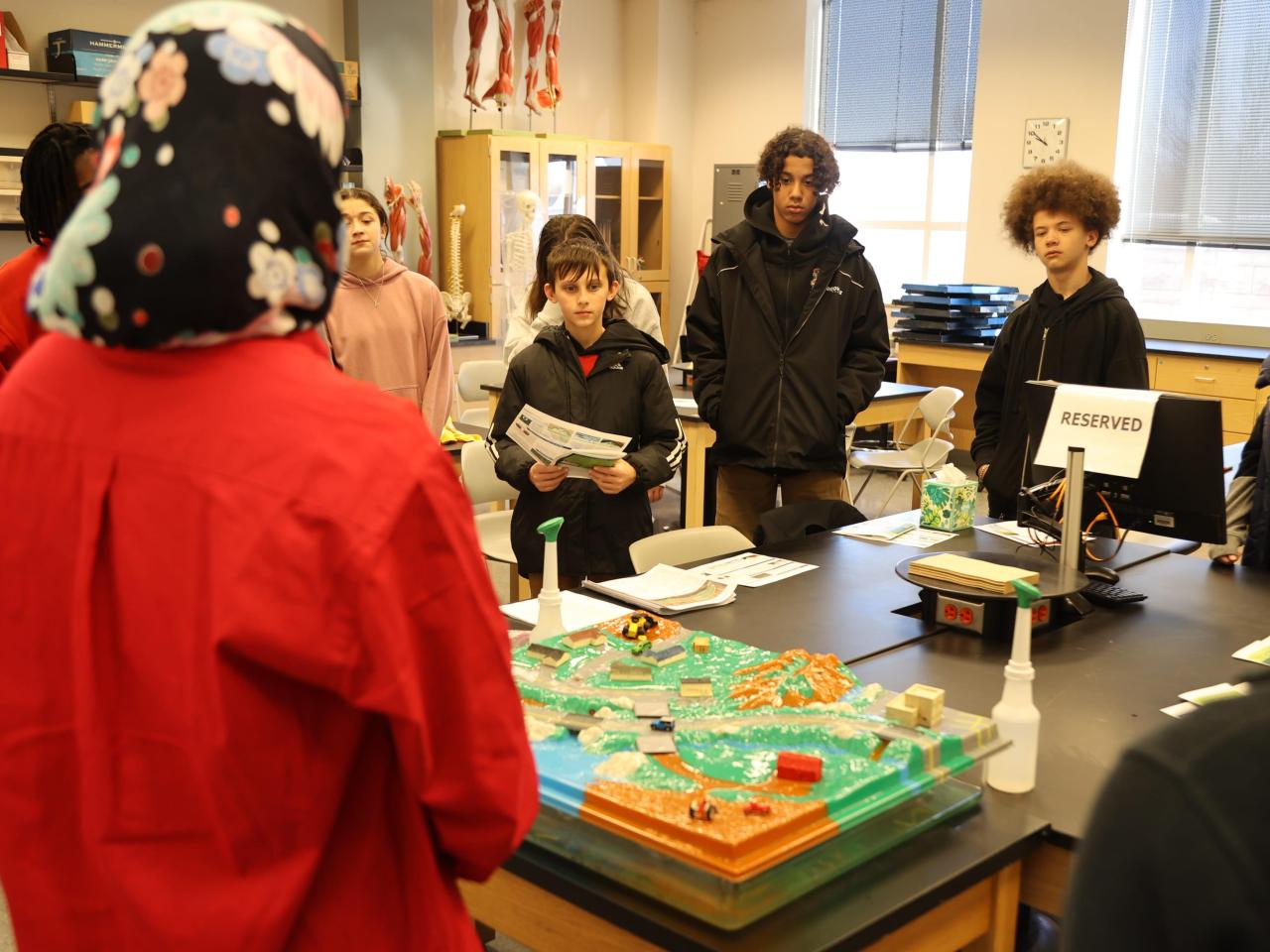 Students in a science lab look at a model of how land use impacts water quality