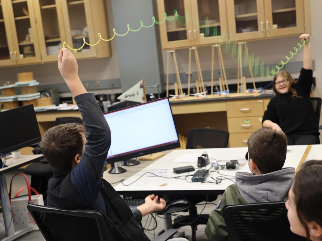 Students in a science lab demonstrate the different types of waves with a Slinky