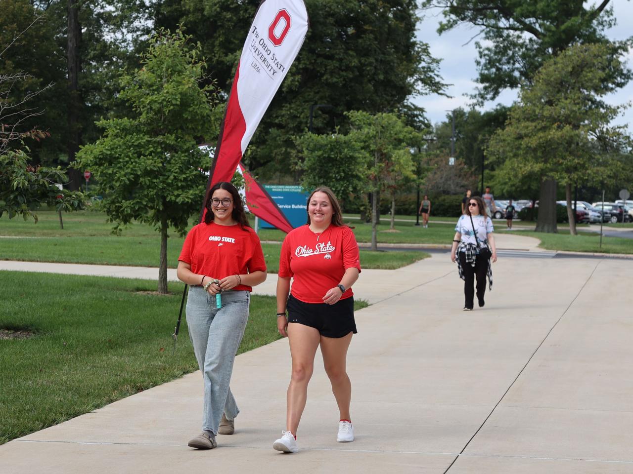 Two students walk in front of an Ohio State Lima flag