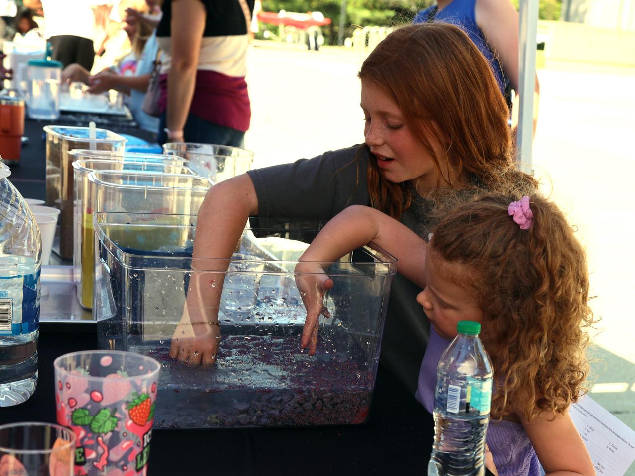 Two children put their hands in colored liquid