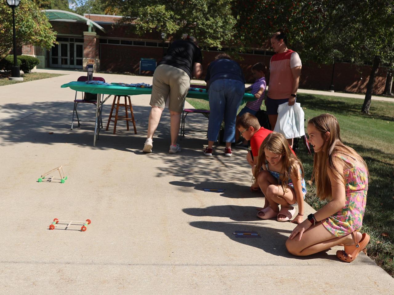 Three children race stick cars at STEAM on the Quad 2025