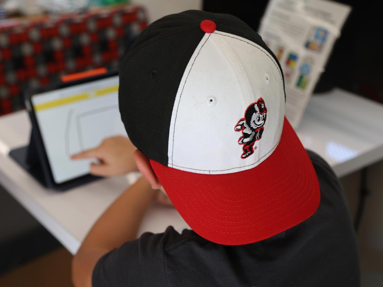 A child in a Buckeye hat looks at a screen