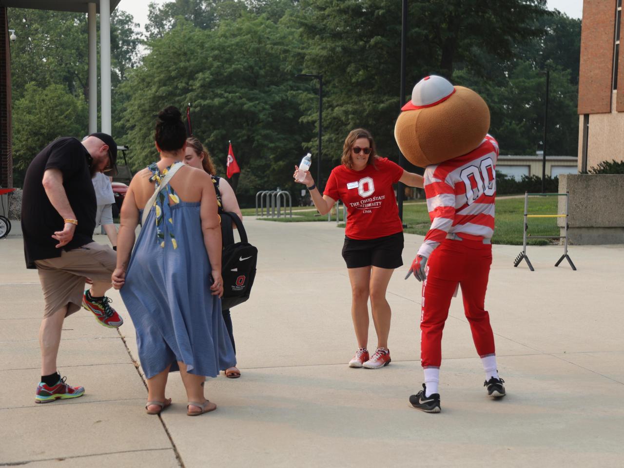 Brutus Buckeye and a group of students dance with the dean in front of Galvin Hall.