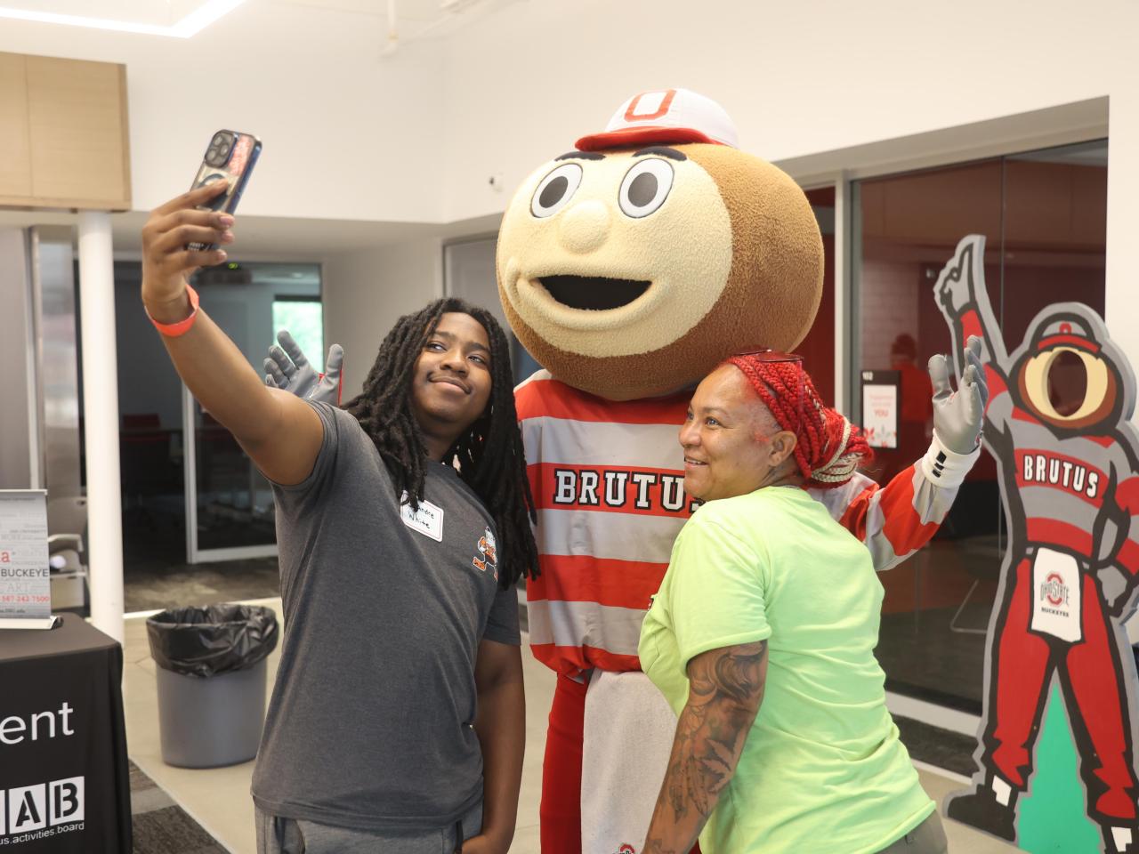 Brutus Buckeye takes a selfie with a student his mother in the Webb. 