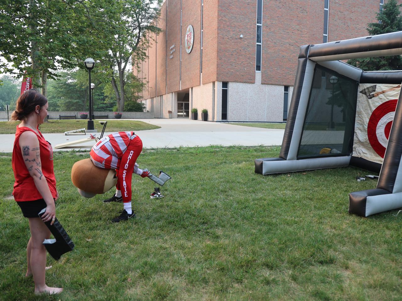 Brutus Buckeye throws a plastic ax backwards through his legs. 