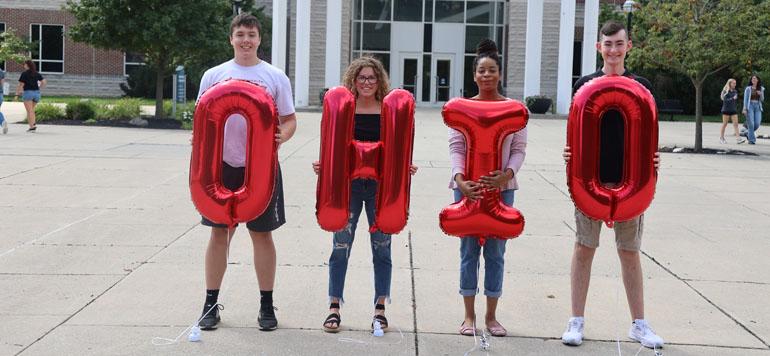 four students holding letter balloons spelling out O H I O