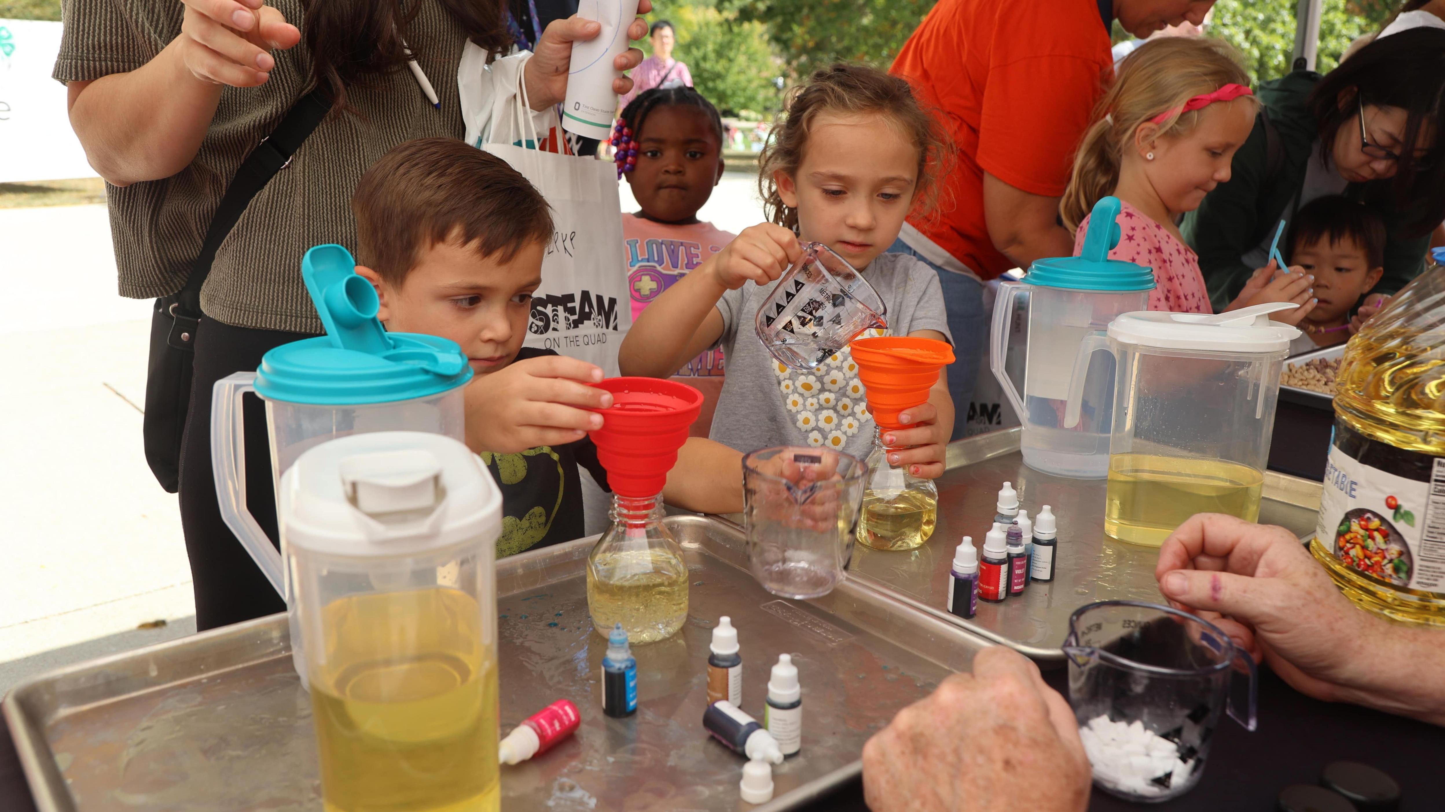 Two STEAM on the Quad participants measure liquids into a beaker 