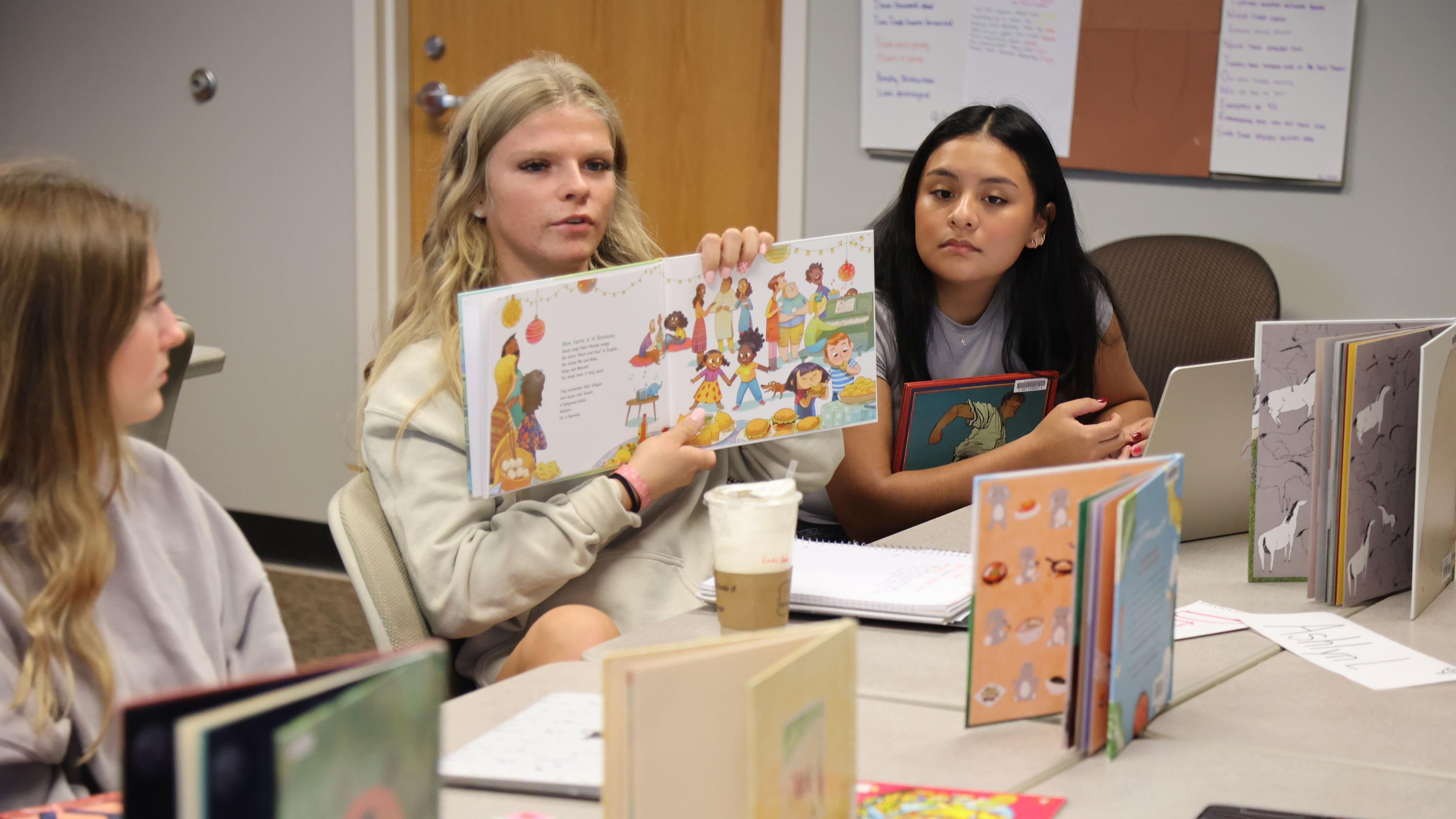 A college student holds up a children's picture book