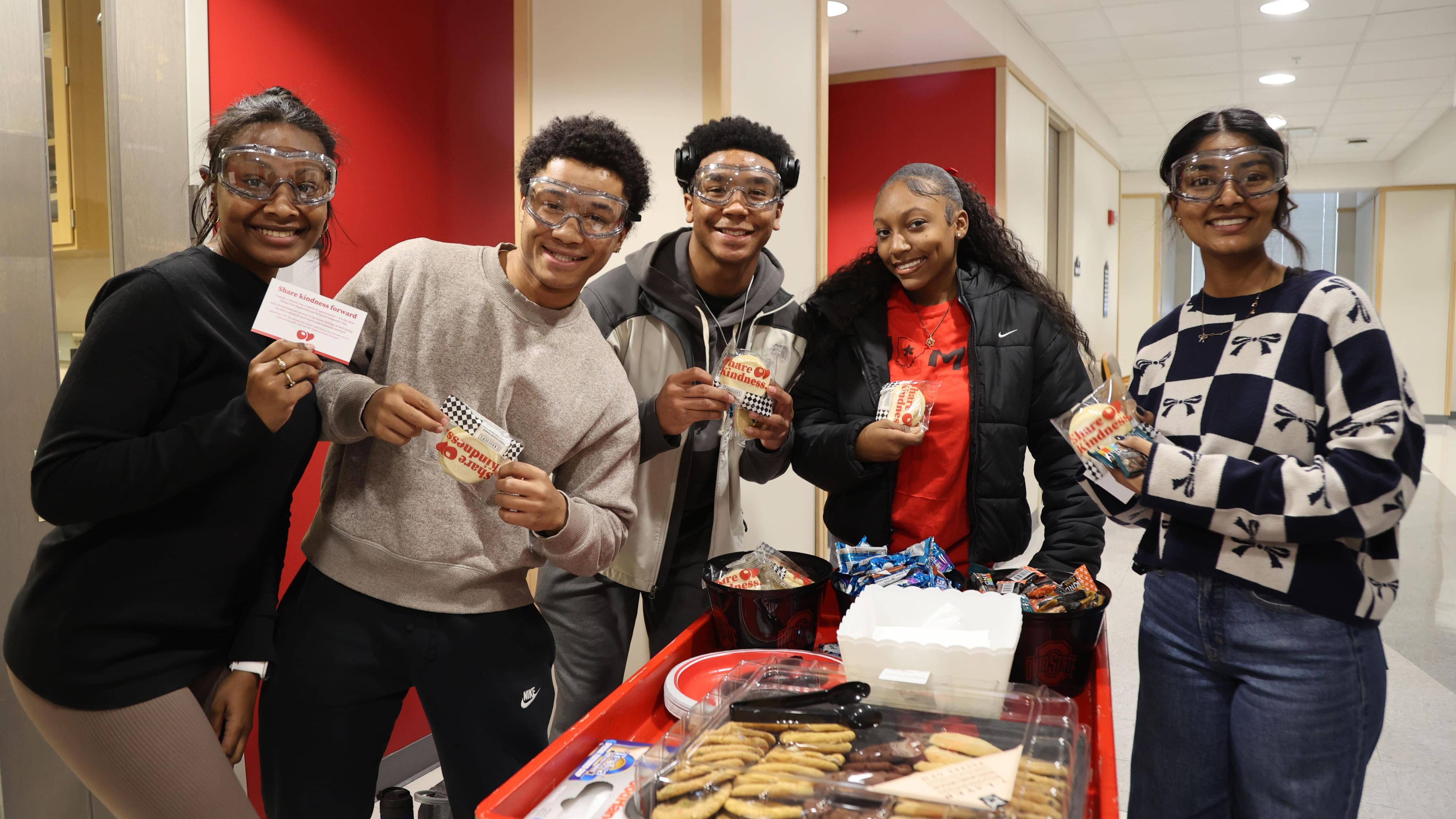 Five students smile around the Share Kindness cookie cart