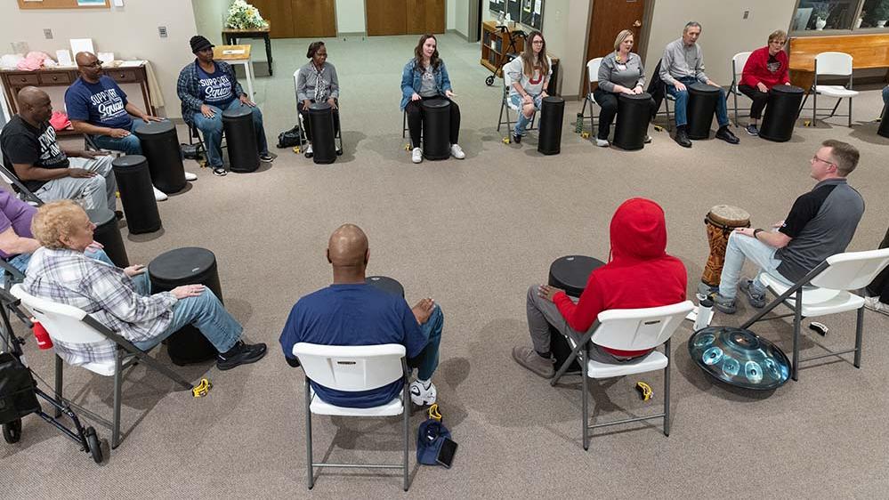 group of individuals arranged in a circle drumming 