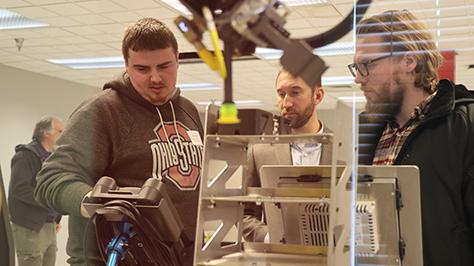 Engineering technology students operate a machine.