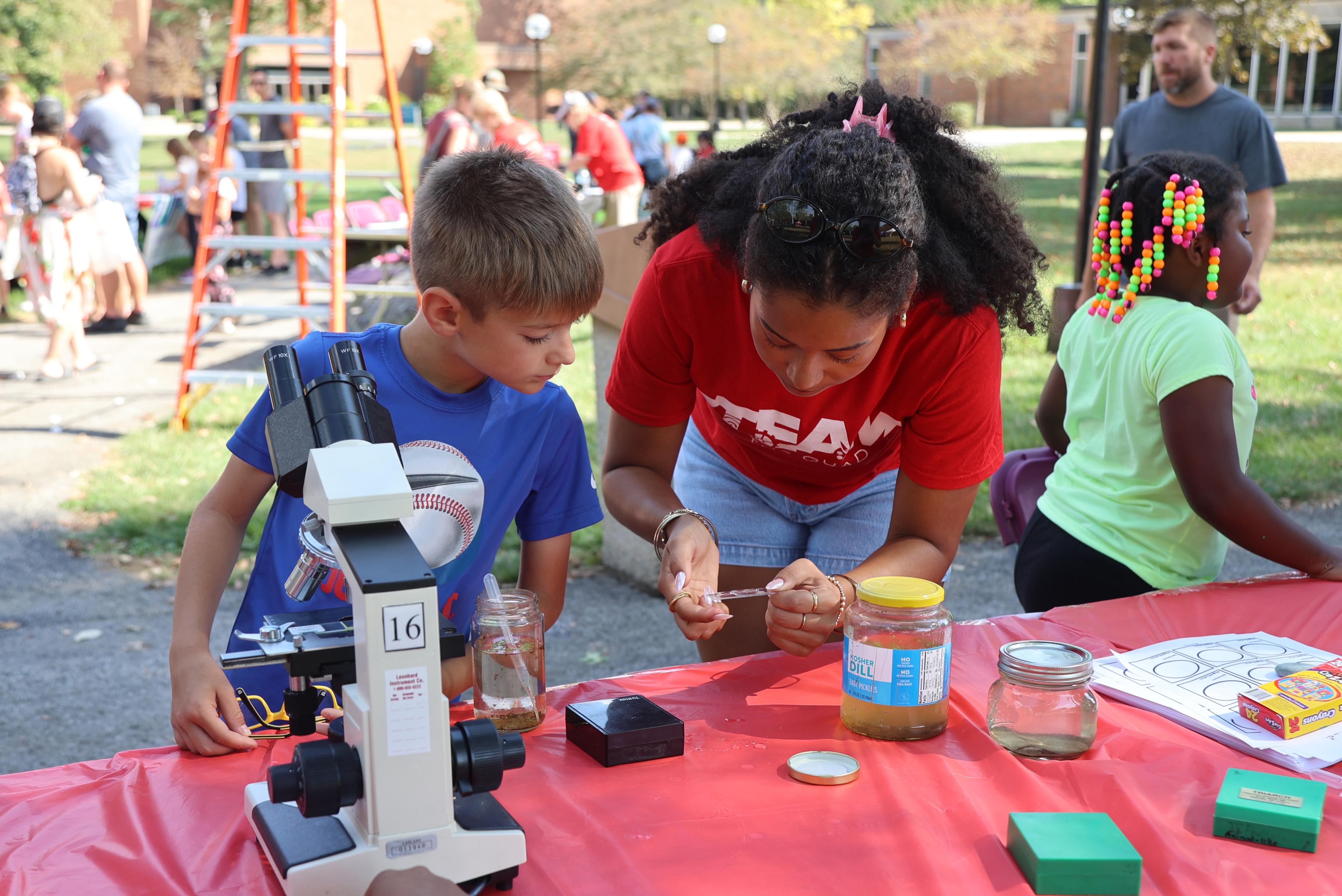 Two people look in a microscope at STEAM on the Quad 2025