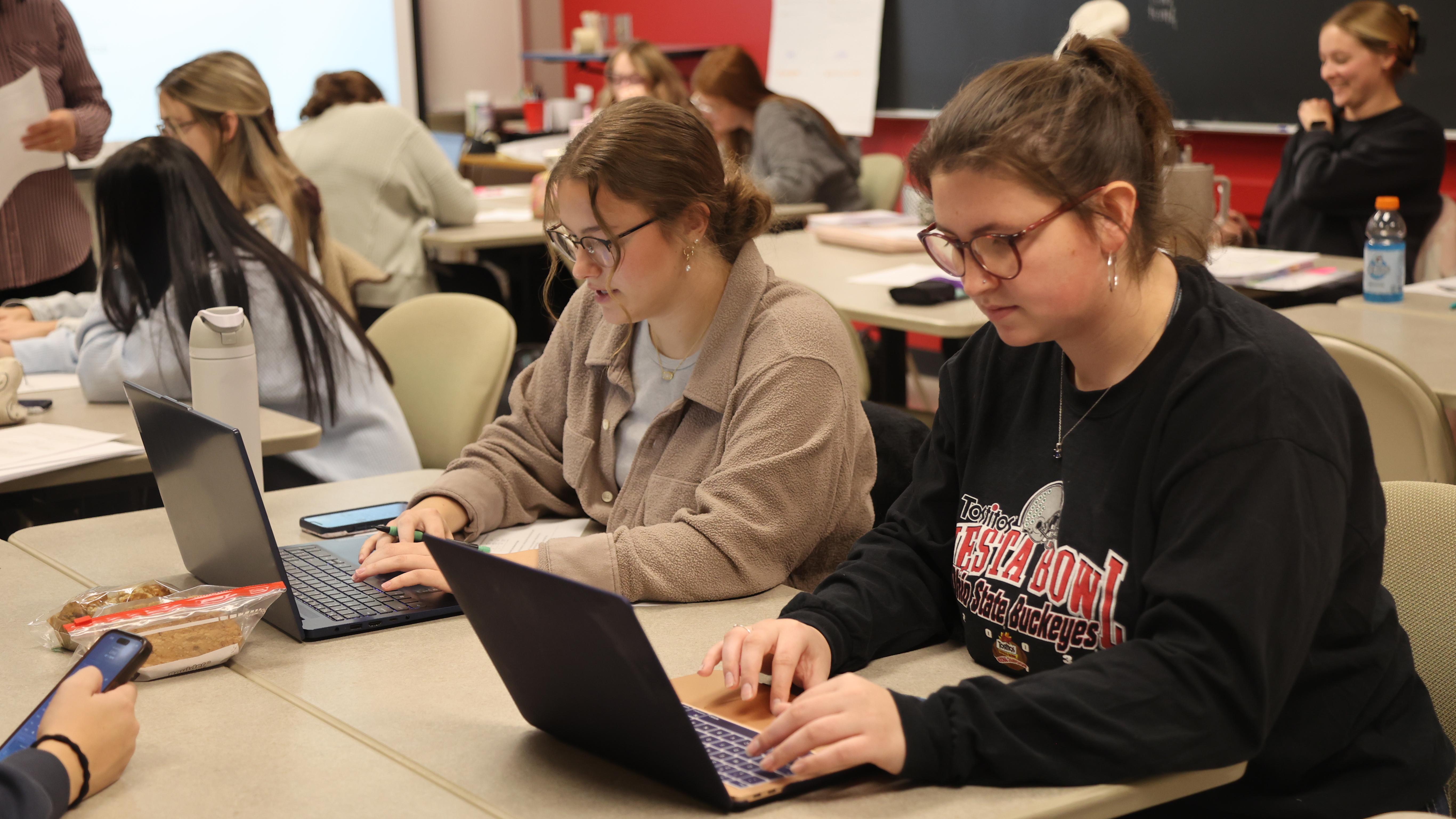 Students with laptops work on an AI assignment in an education classroom