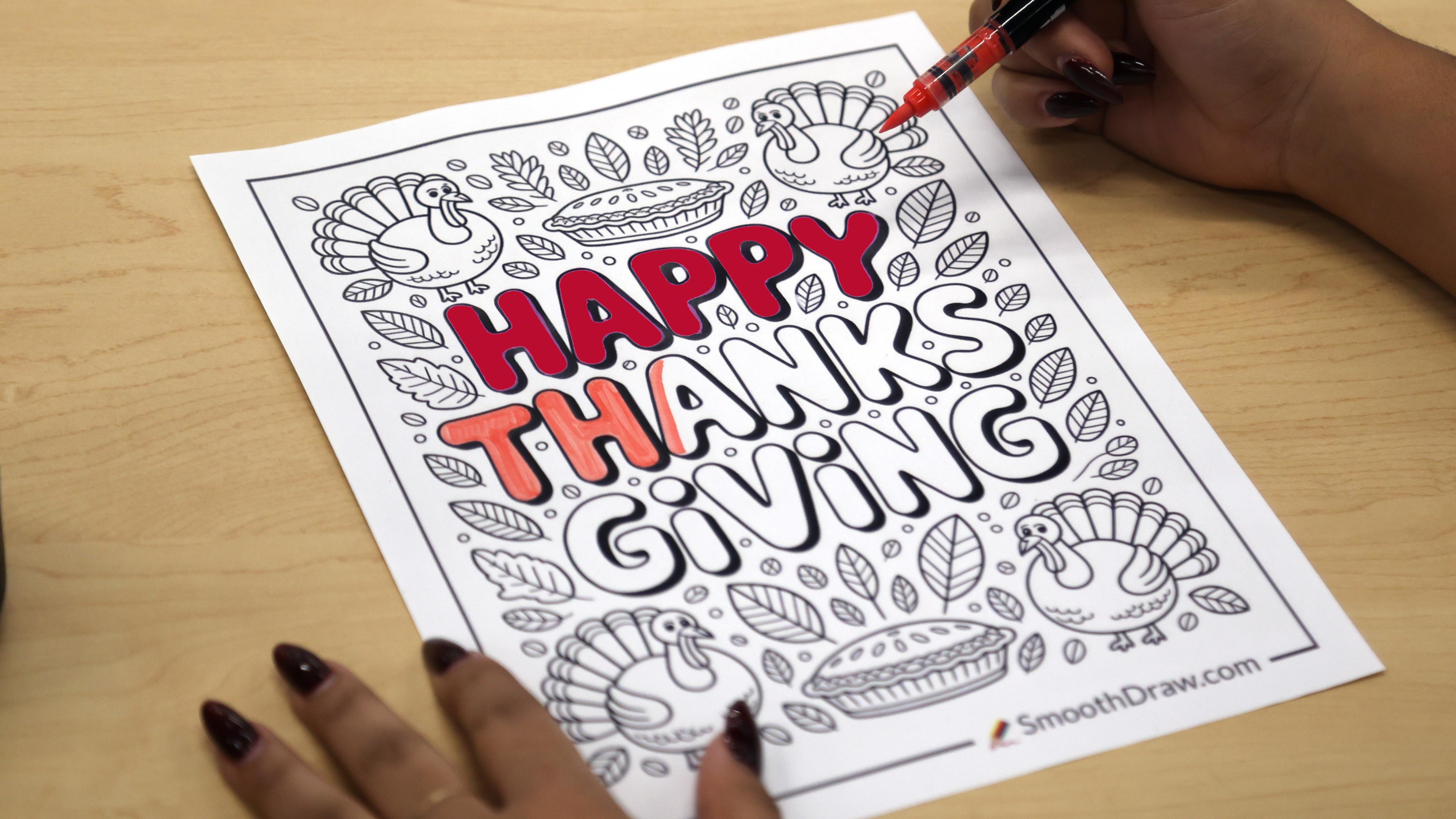 A student inks Happy Thanksgiving on a piece of paper