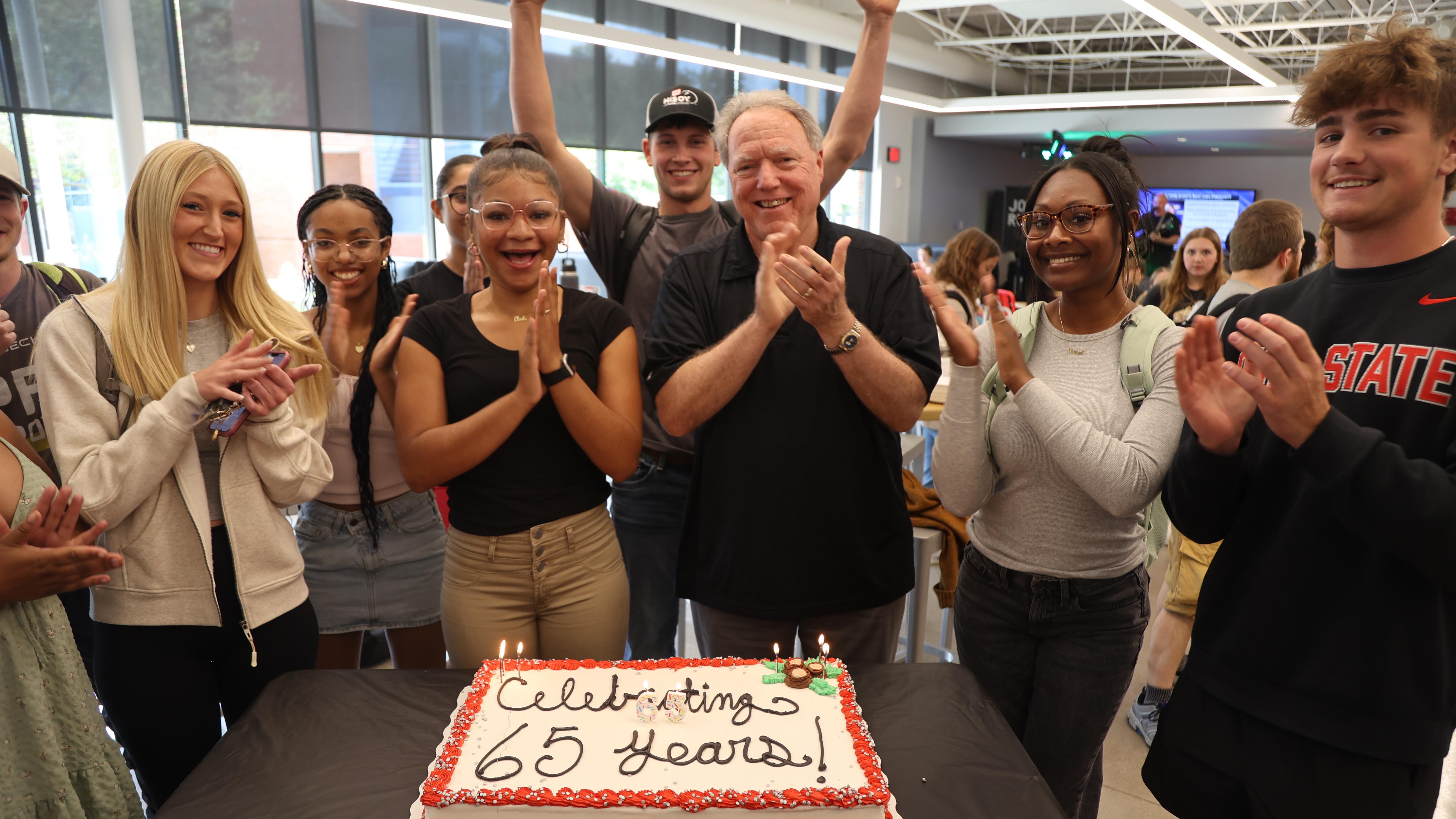 Students and faculty celebrate Ohio State Lima's 65th anniversary with cake. 