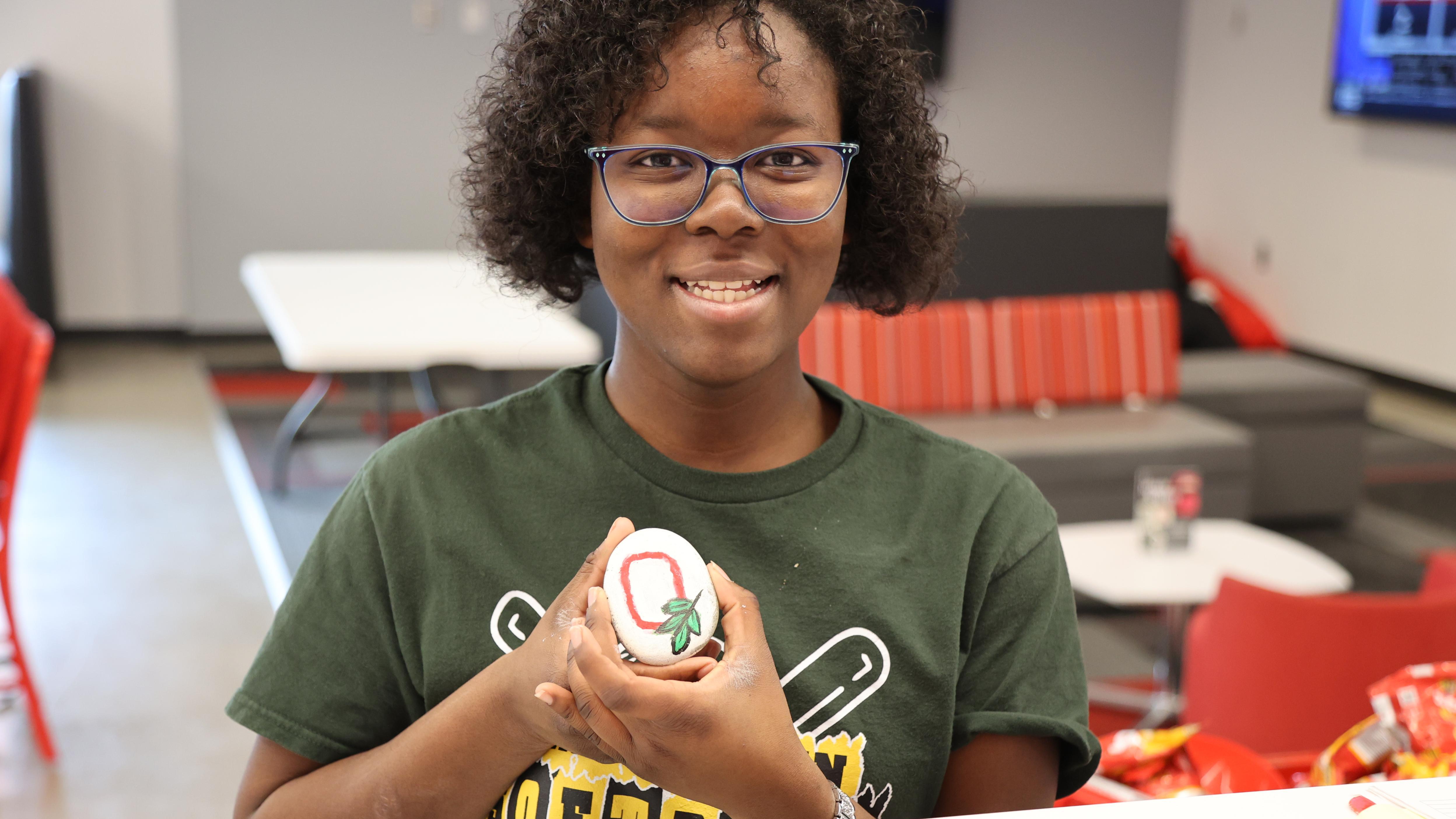 A student holds a kindness rock painted with the Ohio State logo