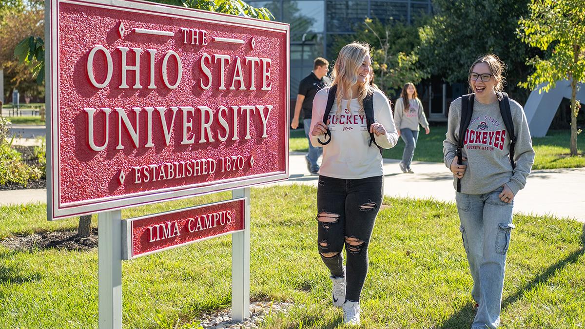 Two students walk by a red sign that says The Ohio State University, Lima Campus