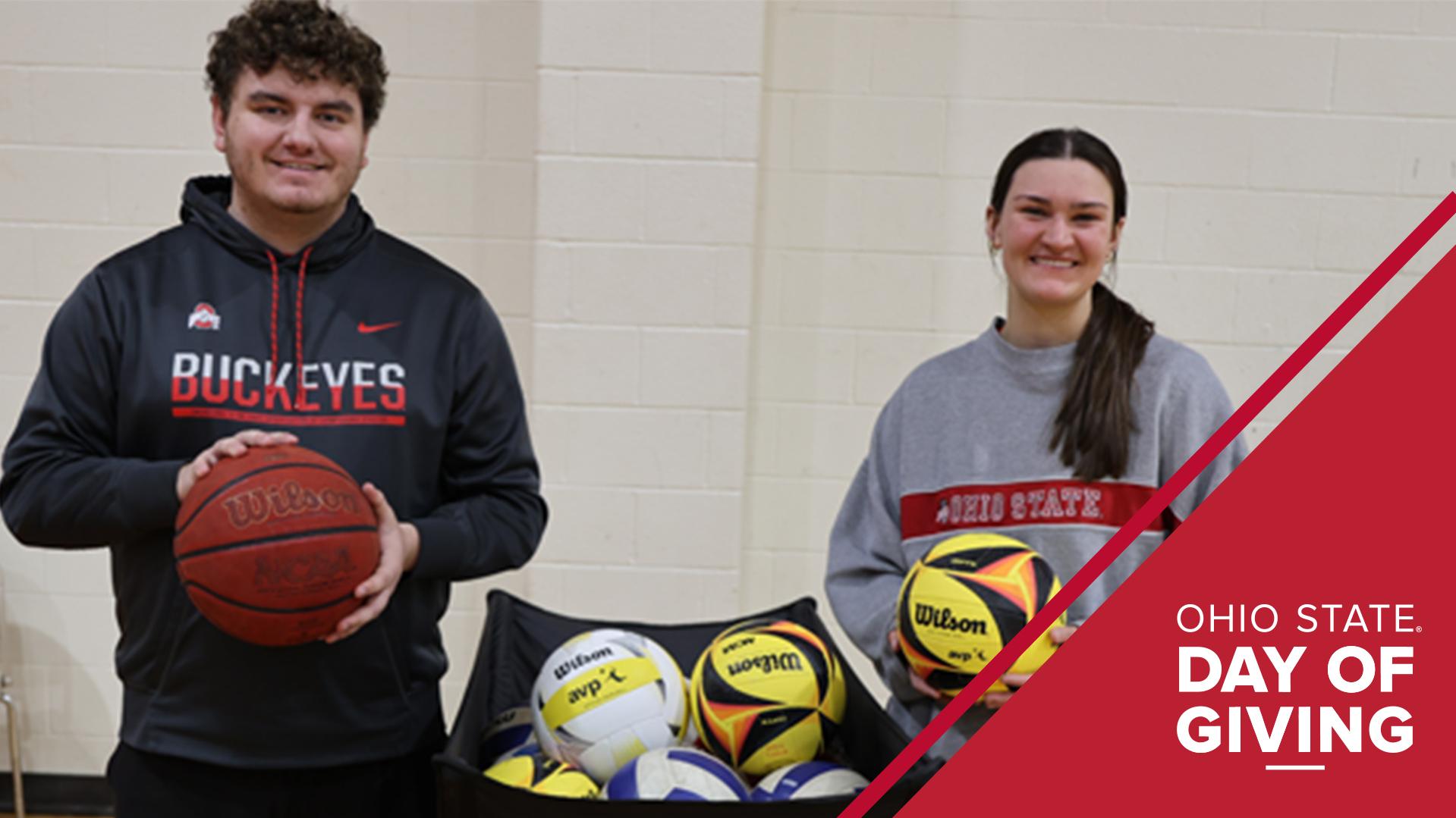 Two students holding balls stand in a gym
