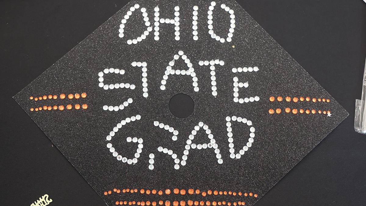 A grad cap with Ohio State Grad written on it in sparkles