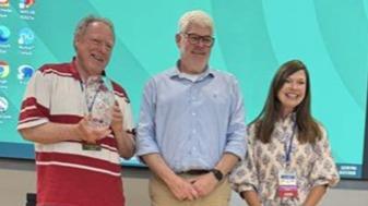 Mark Kleffner holds an award next to another man and woman