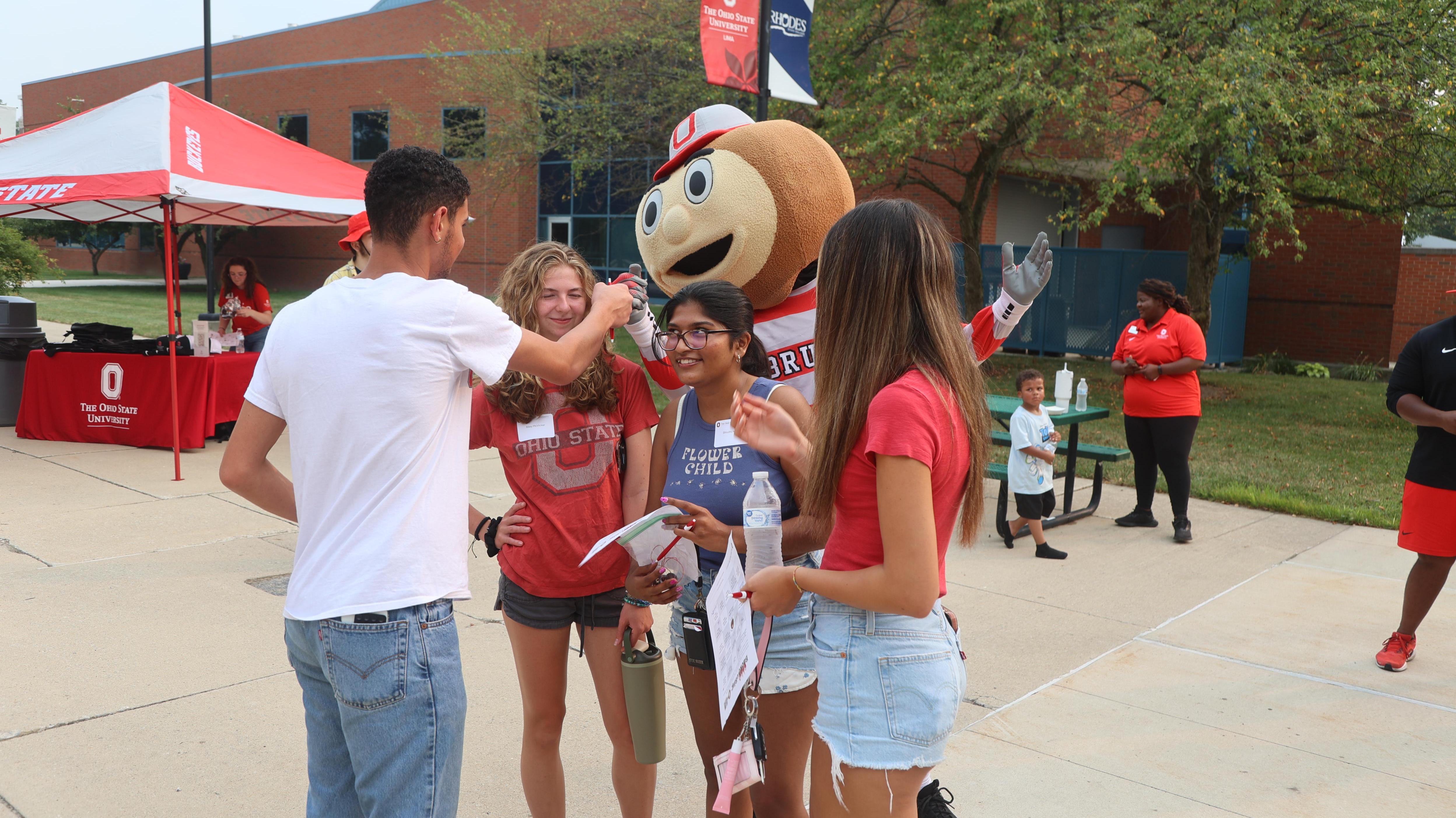 Brutus Buckeye fist bumps a student