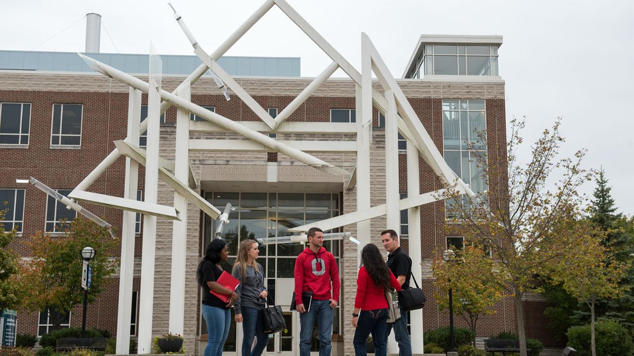 5 students stand outside building at Lima campus