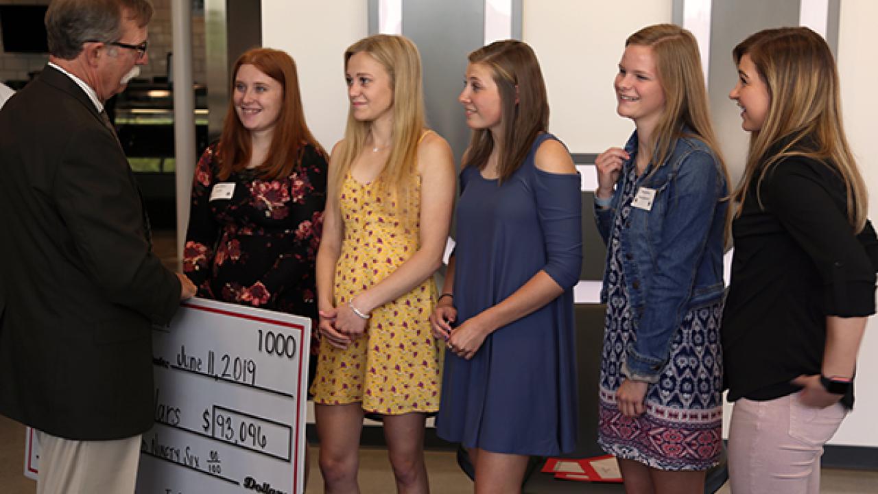 Five girls recieving a scholarship check