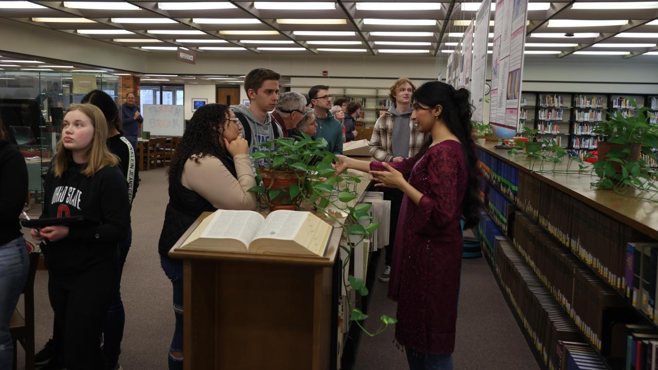 Fatima speaking with other students in a library setting.