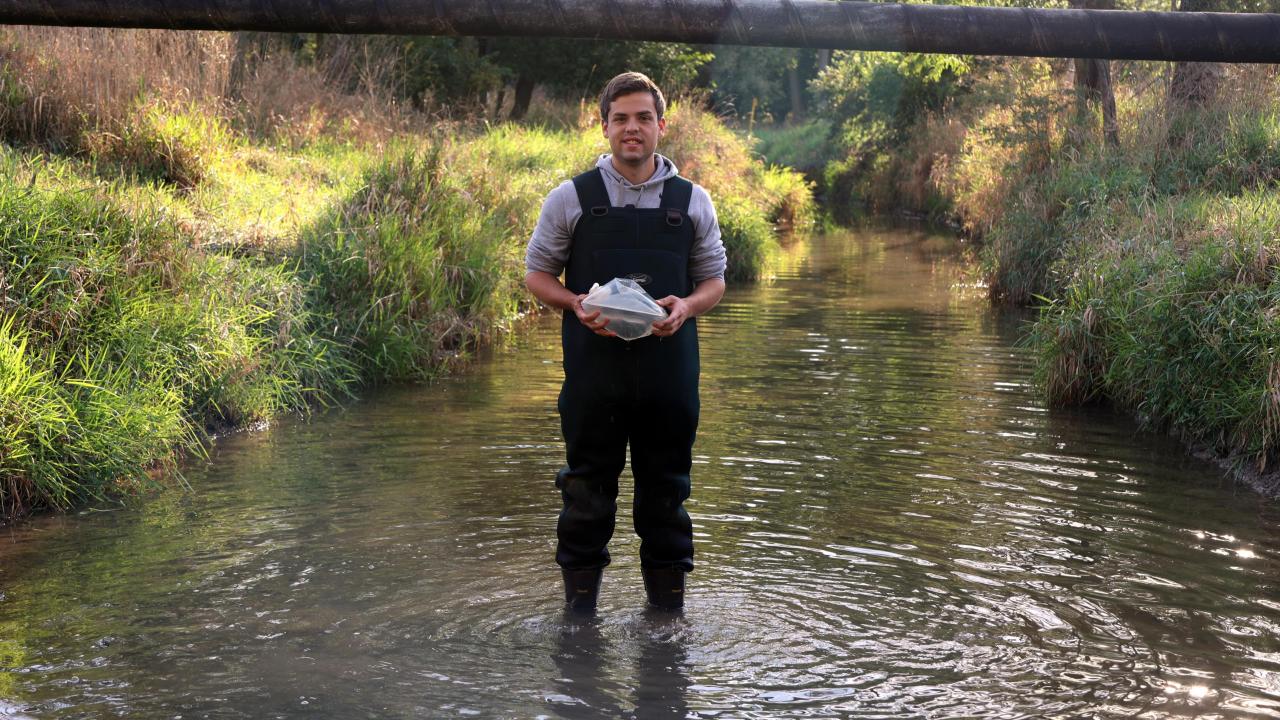 Undergraduate researcher Carter Welch stands in the Lost Creek in waders.